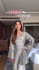 An ode to effortless elegance, this silken grey ensemble is crafted in a flowing sharara silhouette that embodies both grace and comfort. The short shirt is adorned with intricate resham and sequin embroidery, where jewel-toned florals and paisley motifs shimmer against the soft sheen of fabric, while reflective accents and delicate gota borders catch the light with celebratory charm. The fringed dupatta drapes with movement, adding layers of festivity to the design, making it an experience, one