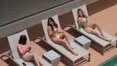 Smiling female friends are sunbathing by the pool on their vacation...