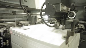 Video clip from the printing factory. Machine for feeding paper in operation. Details of modern equipment.