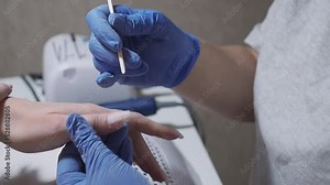 Manicurist makes cuticle removal procedure with wooden stick. Woman hands nail care and manicure in beauty salon