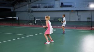 Sporty boy and girl playing tennis on court as team together