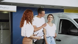 At automobile sales centre. Car salesperson selling new automobile to young family.Beautiful young couple at car showroom choosing a new car to buy