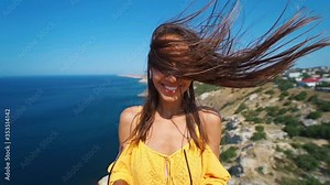 120 fps slow motion closeup beautiful joyful woman in orange sundress with long hair blowing by wind. girl stands on cliff over sea and puts off pink sunglasses at sunny day