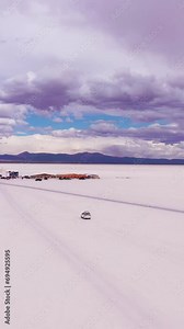 Uyuni Salt Flats and SUV Car. Salar De Uyuni. Aerial View. Altiplano, Bolivia. Dry Season. Orbiting. Wide Shot. Vertical Video