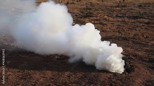 A smoke plume rises from the ground, creating a hazy outdoor atmosphere, implying environmental effects and cinematic transitions
