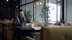 Man Reading Menu at Table in Cafe