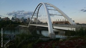 Sunset Time lapse with clouds of the Walterdale Bridge in Edmonton Alberta in a stunning change of the weather while people enjoy fitness romantic walks cycling biking escooters crossing happy people