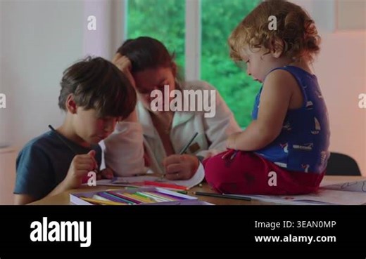 Young child using colored pencils on paper while seated near sibling and mother expressing exploration creativity and early learning within warm domestic environment Stock Video Footage - Alamy