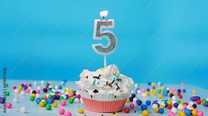 Happy birthday greetings for a 5 year old child, birthday cupcake with candles and birthday decorations on a blue background.