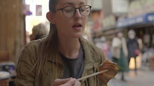 This video shows a woman eating pork belly with chopsticks at an outdoor restaurant.