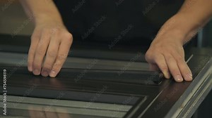 Worker manually assembling the handcrafted parts of the timber window. Worker attaching parts to the handcrafted wood window frame. Worker finishes the manufacturing of the handcrafted window