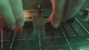 DJ adjusts sound on equalizer by manipulating sliders. Qualified musician tweaks high frequencies to add sparkle and clarity to mix