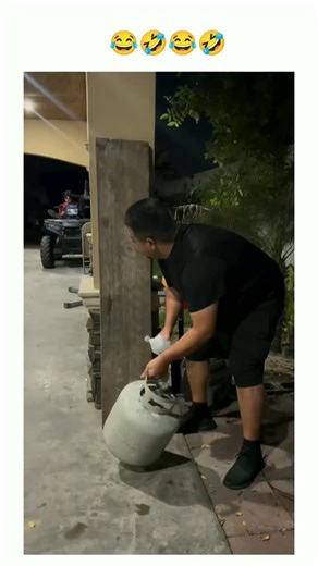 @trendeymemes on Instagram: "The video begins at night in a covered driveway or garage area. A man in a black shirt is seen preparing a propane tank. He is seen spraying an accelerant (likely lighter fluid or a similar flammable liquid) onto the outside of the tank and the ground around it. In the background, two other men are sitting calmly at a folding table, seemingly unaware of the extent of the prank about to occur. ​The Incident ​The man with the tank uses a lighter to ignite the fluid. Im