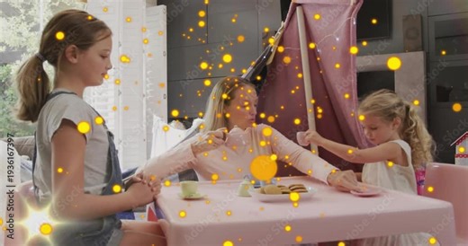 Caregiver lifting teapot causing childcare sparkles flaring while two girls reaching cups for play