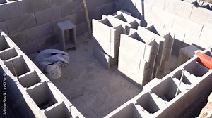 Reinforced foundation layout with cinder blocks and utility piping on construction site
