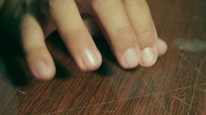 Man knocks fingers on the table. Makes rhythmic beats.