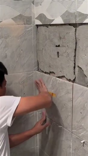 the process of installing rectangular ceramic tiles on walls in a room in a building #construction