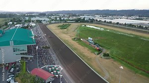 Cinematic 4K aerial drone shot of a horse race at Emerald Downs, a thoroughbred racetrack with a green grandstand in Auburn, Washington, near Highway 167