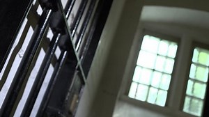 Prison door slamming shut. Bright window in background, old black metal cell door slams shut, close up of bars.