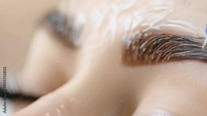 A highly detailed close-up of a microblading procedure on a Caucasian woman's eyebrow. The technician precisely applies pigment using a handheld tool. The setting seems clinical, focused, and