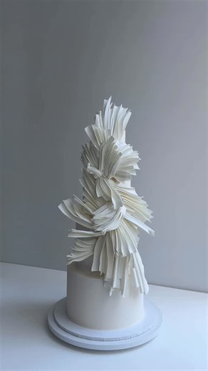 K CAKE on Instagram: "A little drapery-style moment today — not the usual ruffles, more like soft folds with a hint of fabric shaping. We worked with gum paste for this one and shaped each piece almost like a fabric twist, pressed and textured, then pre-dried before going onto the cake. Finished with a heavy cocoa-butter spray so everything locks in together and stays moisture-proof. Just something new we’ve been trying out lately."