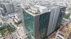 Aerial cinematic video showcasing a commercial highrise building's installation of sustainable solar panels for partial energy consumption.