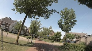 4k video of girl cycling through residential street in the Netherlands with wide cycle lane, green hedge and no cars. Urbanism design for slow transportation neighbourhood
