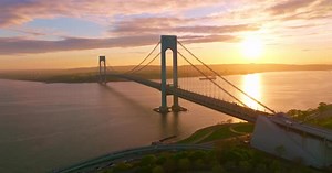Whitestone Bridge over East River at setting sun. Sun reflecting in the calm water.
