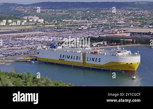 KOPER PORT, SLOVENIA - 2024, March 3: AERIAL: Large Grimaldi Lines cargo ship sits docked in Luka Koper, loading cars from the parking lot. Freight ship in Koper port unloads cargo on a sunny day Stock Video Footage - Alamy