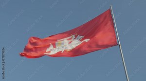 The historical state flag of Lithuania. The coat of arms of Lithuania, consisting of an armor-clad knight on horseback holding a sword and shield, is also known as Vytis. Blue sky background.