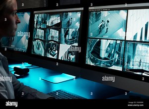 Focus on desktop computer monitors with cctv video system on screens standing in front of young working female guard Stock Photo - Alamy