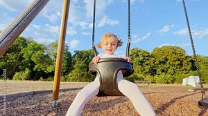 Cute beautiful little girl ride sitting on swings at playground