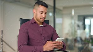 Busy latin business man sitting in office chair holding phone working on smartphone. Smiling professional young businessman using mobile cell phone looking at cellphone technology device at work.