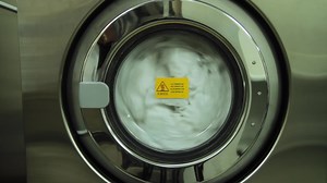 Washing machine turning close-up. Scene. Industrial washer machine working. Close-up of laundry clothes in industry washing machine