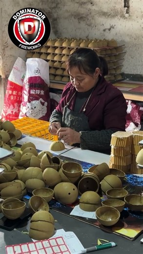 Preparing ball shells for production requires many steps. A worker installs tubes for time fuse.