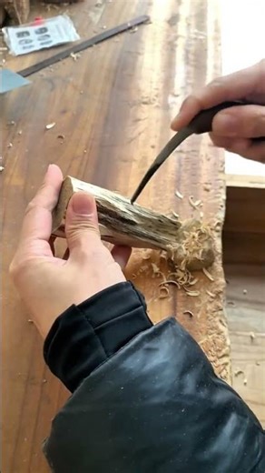 Woodworker carving small wooden piece using sharp handheld chisel tool
