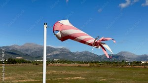 White and orange windsock spinning on strong wing on beautiful sunny day Stock Video