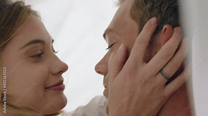 happy young couple lying in bed kissing under sheets sharing romantic relationship enjoying intimacy together at home 4k