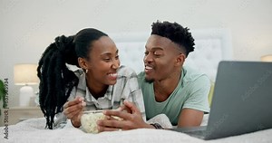 Popcorn, bed and couple on laptop for movie, online streaming and watching film at home. Relax, love and happy African man and woman in bedroom with snack series subscription on computer for bonding