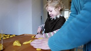 A little boy baking buns and cut the dough