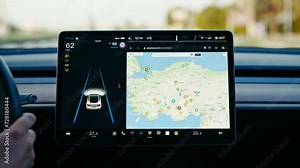 Close-up of Tesla car sensor touchscreen monitor with different apps, functions and capabilities, autonomous navigating system controlling road traffic, speed and battery