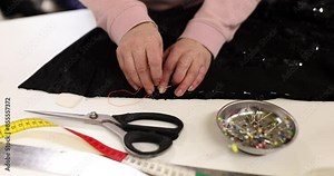 Woman seamstress makes even stitches basting fabric along edge