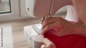 Woman sews on the modern sewing machine. Sewing machine sews close up the action in slow motion.
