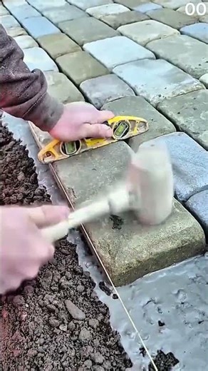 Rubber mallet taps paving stone spirit level checks alignment