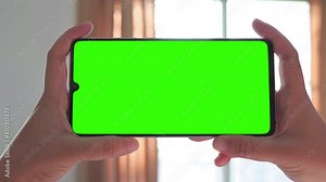 Horizontal hands holding smartphone with green screen. Green screen mobile phone with chroma key. Perfect for product placement.
