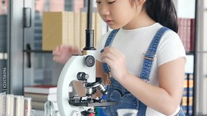 Little girl learning how to use microscope by herself. People with science and education concept.