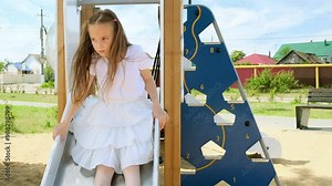 Adorable little girls plays on the playground. A children slides down a slide. Happy childhood concept
