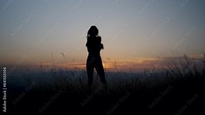 Silhouette of a happy woman taking off her clothes and dancing in the nature.Freedom concept