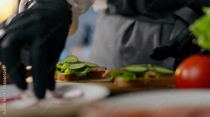 Fast food, sandwich master is deeply involved Spreads ingredients vegetables cooking burger in sandwich lab. Close-up of a skilled craftsman working at the workplace of a vegan cook, lunch