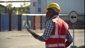african american Foreman using tablet computer checking inventory control loading Containers at warehouse logistic in Cargo freight ship for import export. engineer and transportation hot in sun light